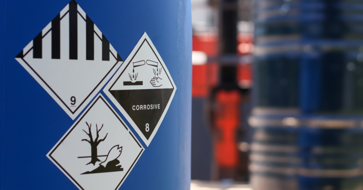 Hazardous material labels for miscellaneous dangerous goods, corrosive substances, and environmental hazards displayed on a chemical drum.